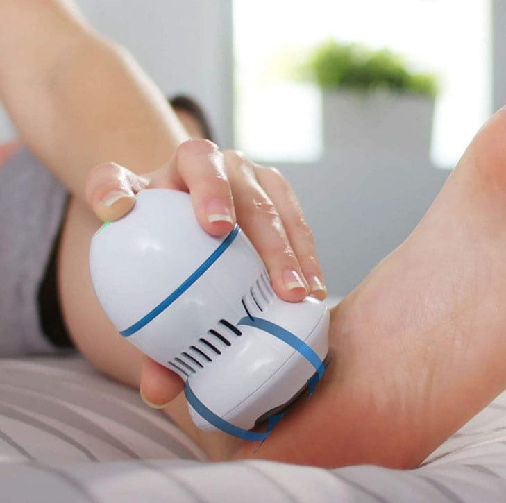 Supersonic electric foot file grinder removing dead skin and calluses from a person's foot, handheld device with exfoliating roller.